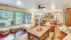 A spacious living room with a large window, a ceiling fan, and a kitchen area in the background. - Fishing & Rafting: Mckenzie River Cabin! (Blue River)