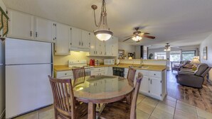 A spacious kitchen with white cabinets, a glass dining table, wooden chairs, and a ceiling fan. - Ruidoso Condo w/ Golf View ~ 17 Mi to Ski Apache! (Ruidoso)