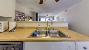 A kitchen with a double sink, a microwave, and a ceiling fan. - Ruidoso Condo w/ Golf View ~ 17 Mi to Ski Apache! (Ruidoso)