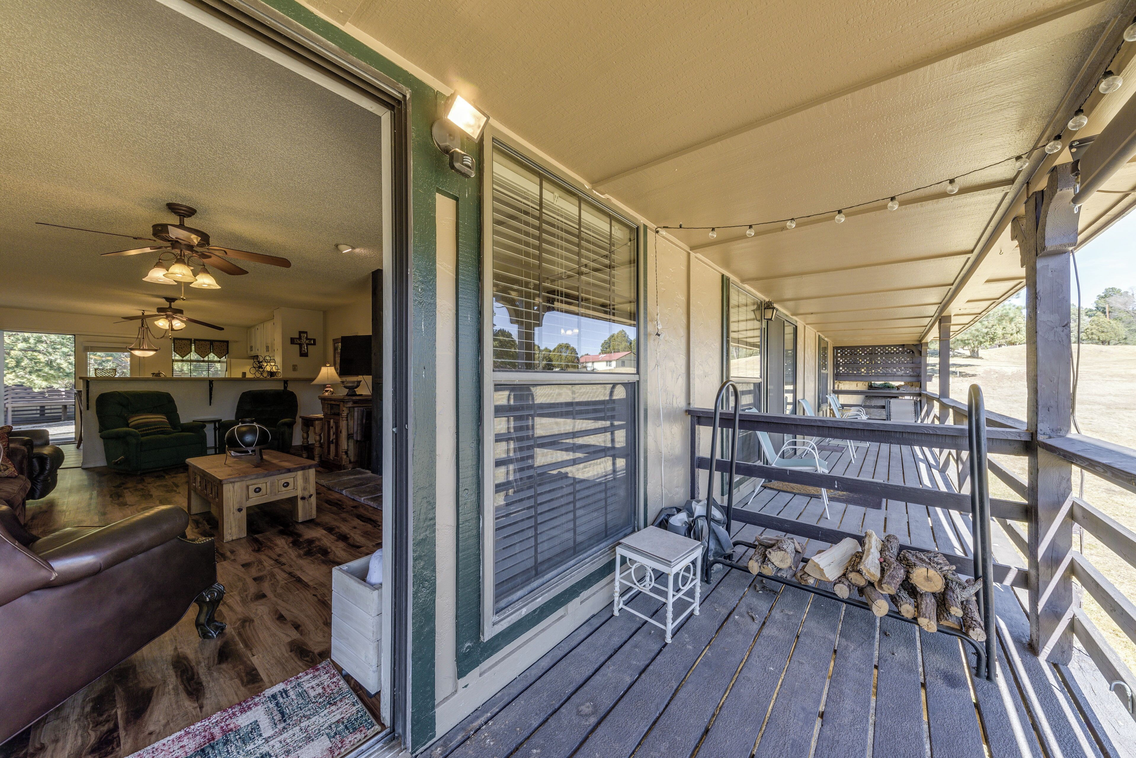 A covered porch with a wooden floor, a small table, and a bench.