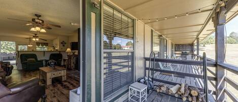 A covered porch with a wooden floor, a small table, and a bench.