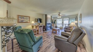 A spacious living room with a fireplace, green and brown leather sofas, and a wooden floor. - Ruidoso Condo w/ Golf View ~ 17 Mi to Ski Apache! (Ruidoso)
