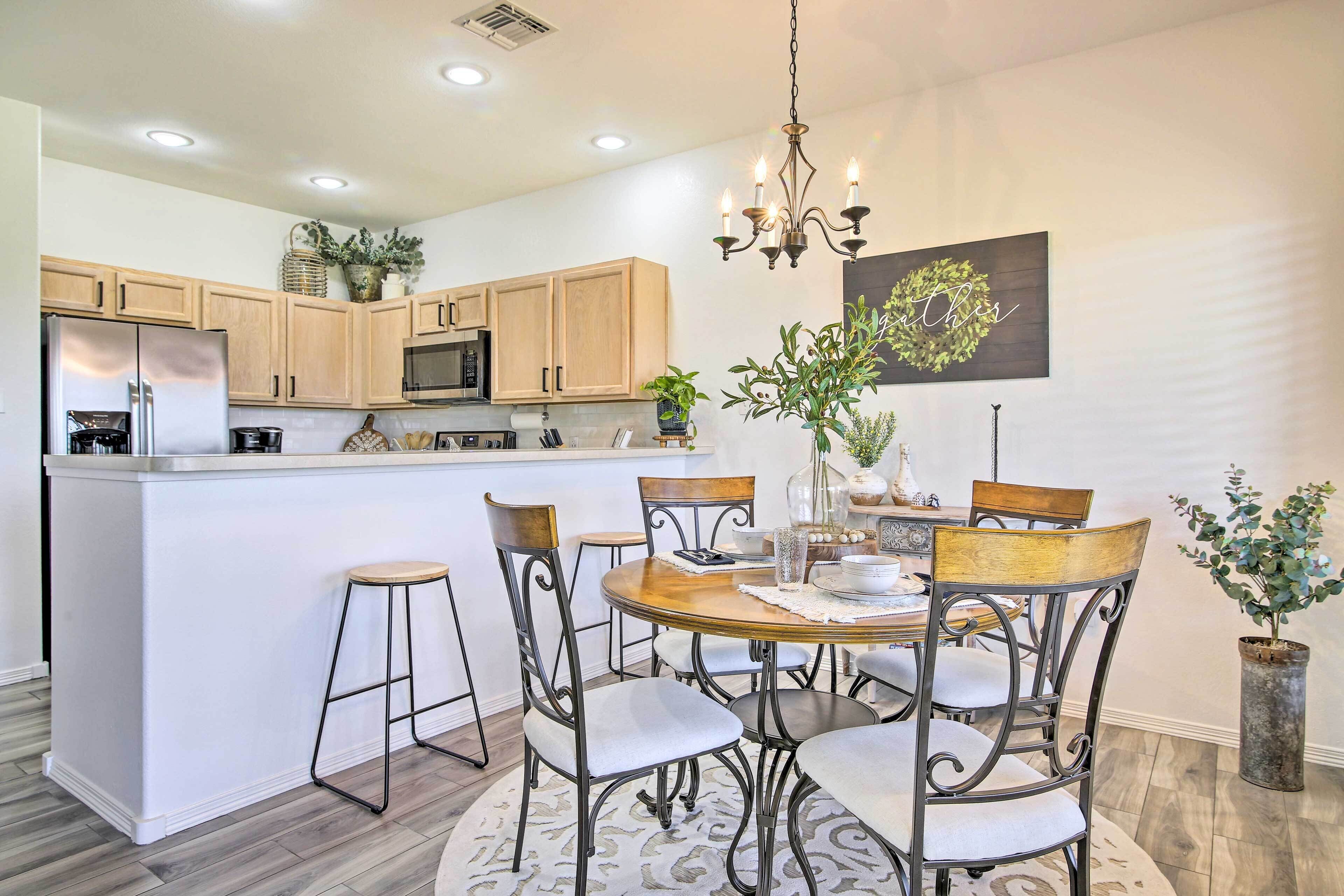 A modern kitchen with wooden cabinets, a central island, and a dining area with a round table and chairs.