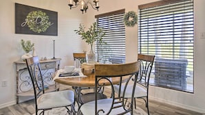 Un coin repas avec une table en bois, des chaises en métal, un lustre et des guirlandes décoratives accrochées aux murs.