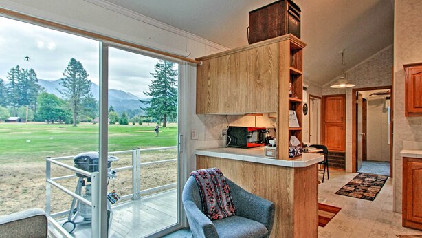 A modern kitchen with wooden cabinets, a built-in microwave, and a large window overlooking a grassy area. - Woodsy Packwood Haven w/ Golf Course Access! (Packwood)
