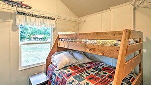 A bunk bed with a patterned quilt, a small bedside table, and a window with a view of a house and trees. - Woodsy Packwood Haven w/ Golf Course Access! (Packwood)