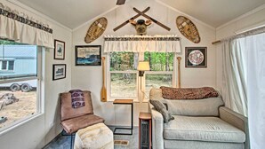 A cozy living room with a ceiling fan, two sofas, a small table, and a window with a view of the outdoors. - Woodsy Packwood Haven w/ Golf Course Access! (Packwood)