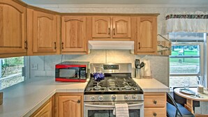 A kitchen with wooden cabinets, a stainless steel stove, a red microwave, and a view of a golf course through the window. - Woodsy Packwood Haven w/ Golf Course Access! (Packwood)