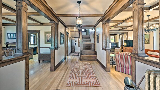 Un hall d’entrée spacieux avec des poutres en bois, un tapis à motifs et un escalier menant à un autre niveau.
