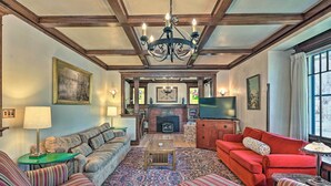 Un salon avec une cheminée, un canapé, un divan rouge et un tapis à motifs.