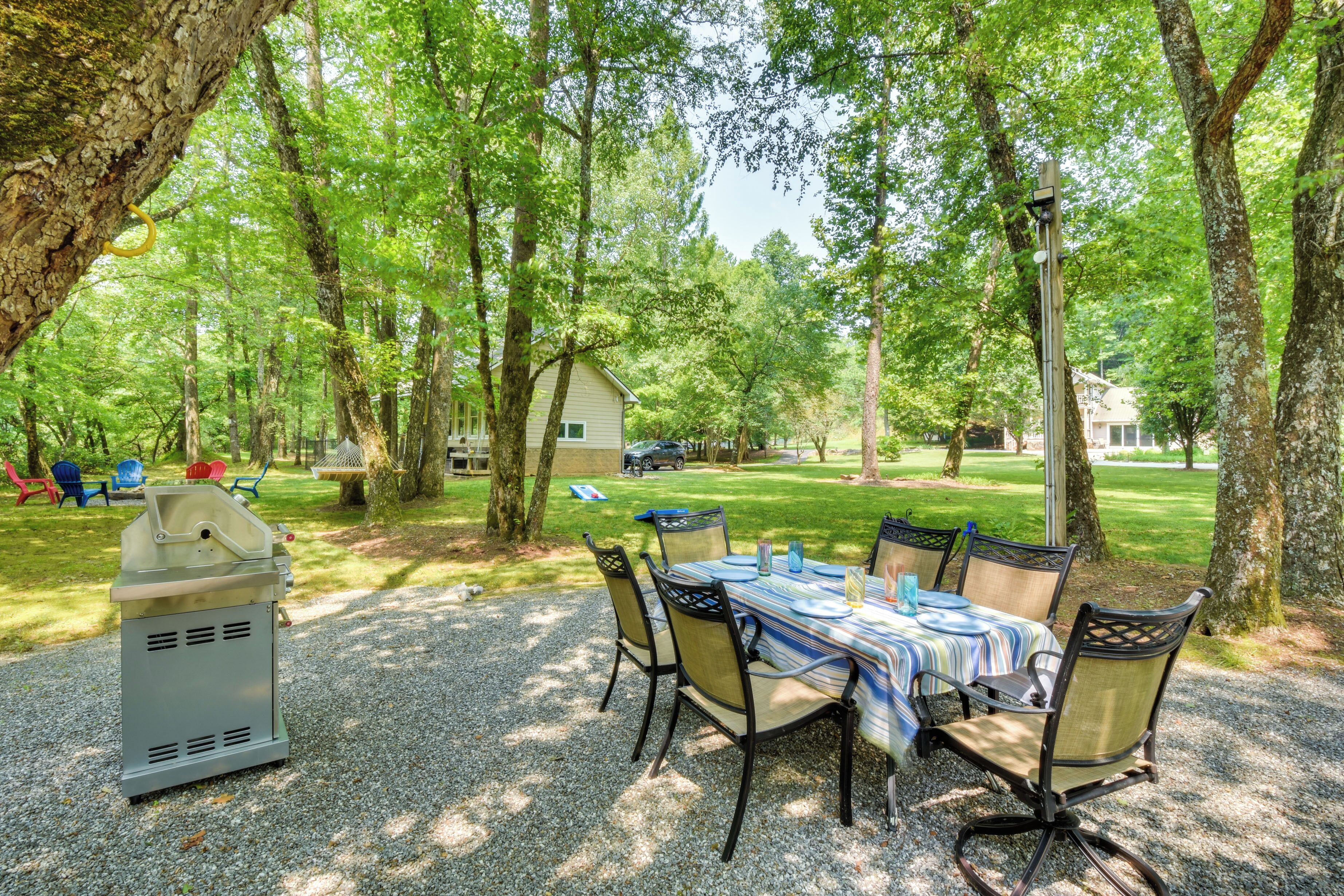 Un espace extérieur abrité, aménagé pour prendre les repas, avec une table et des chaises, entouré d’arbres.