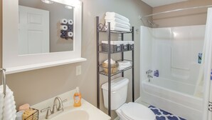 A bathroom with a sink, toilet, and bathtub. There is a shelf with towels and toiletries. - Walk to Main St: Inviting Byrdstown Home w/ Yard! (Byrdstown)