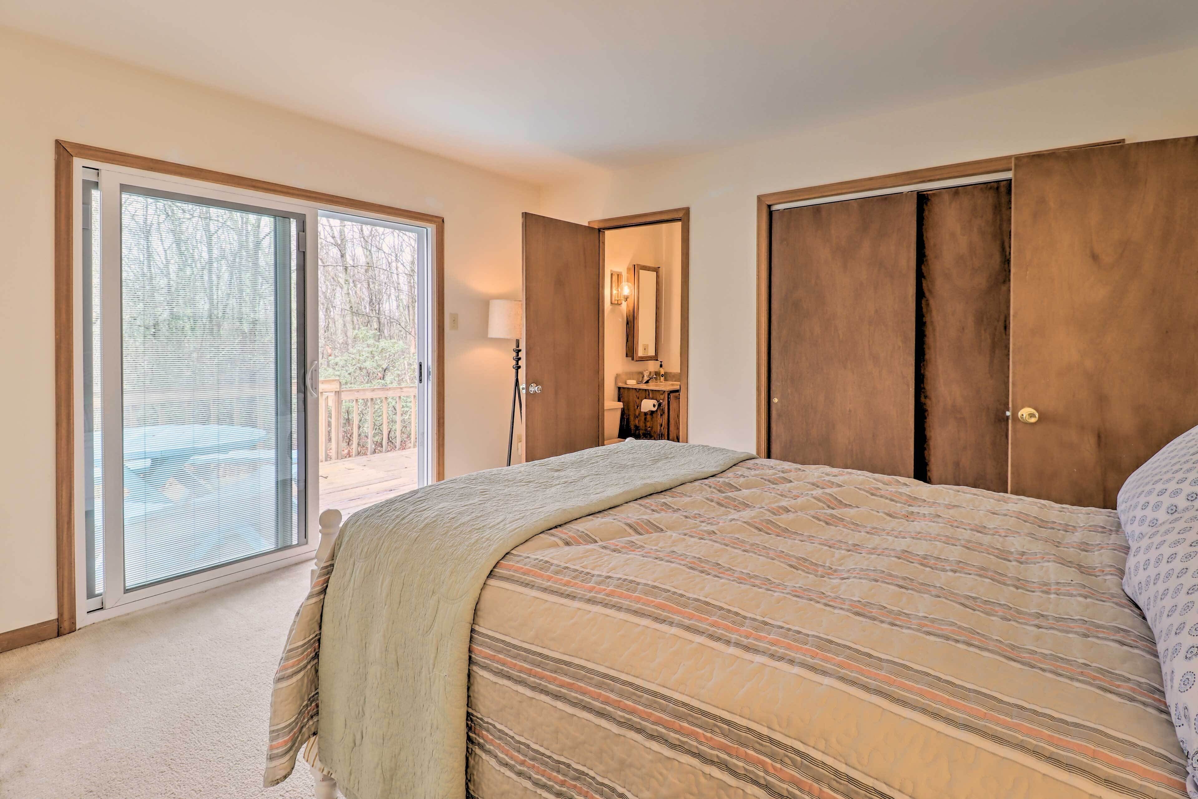 Une chambre avec un grand lit, une porte-fenêtre coulissante donnant sur un balcon et une armoire en bois.