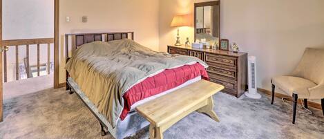 Un dormitorio con una cama, un banco de madera, un aparador, una silla y un calentador.