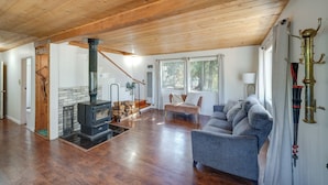 A spacious living area with a wooden ceiling, a fireplace, a sofa, and a staircase leading to another level. - Quiet Sequoia National Forest Cabin w/ Fireplace (Posey)