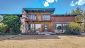 A two-story house with a stone facade, large windows, and a wooden deck. - Spacious Pinedale Home w/ Mountain Range View (Pinedale)