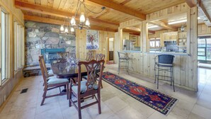 A wooden interior with a stone wall, a dining table with chairs, a kitchen area, and a bar. - Spacious Pinedale Home w/ Mountain Range View (Pinedale)