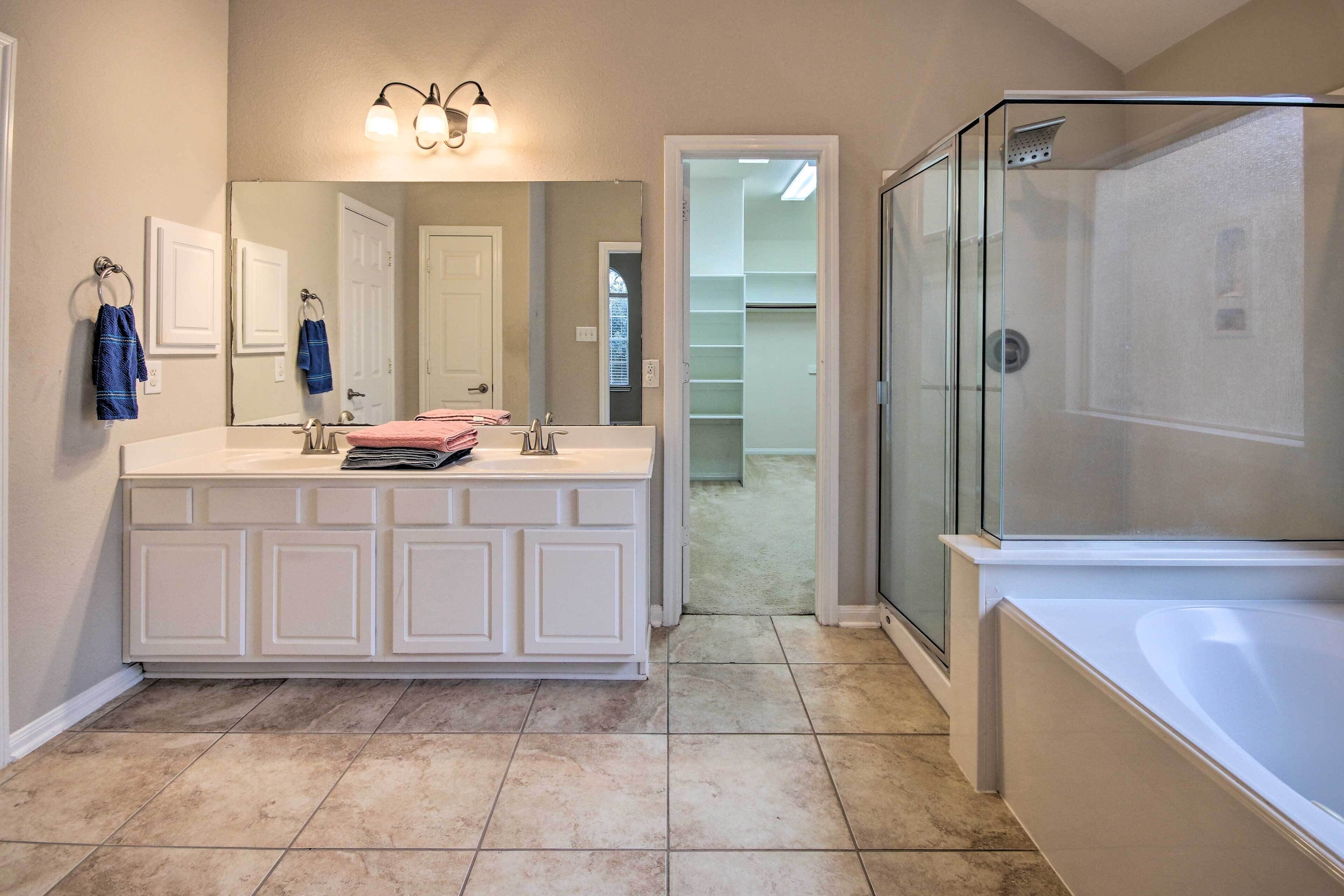 A bathroom with a large vanity, a walk-in shower, and a mirror above the vanity.