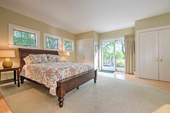 A bedroom with a large bed, a nightstand, a lamp, and a view of the outdoors through a sliding glass door.