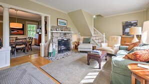 A spacious living room with a stone fireplace, a dining area with a wooden table and chairs, and a staircase leading to an upper level. - Southwest Harbor Home-3 Min to Acadia Natl Park (Southwest Harbor)