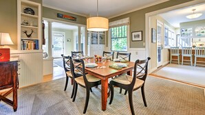 A dining room with a wooden table, six chairs, and a chandelier. There is a kitchen visible through an open doorway. - Southwest Harbor Home-3 Min to Acadia Natl Park (Southwest Harbor)