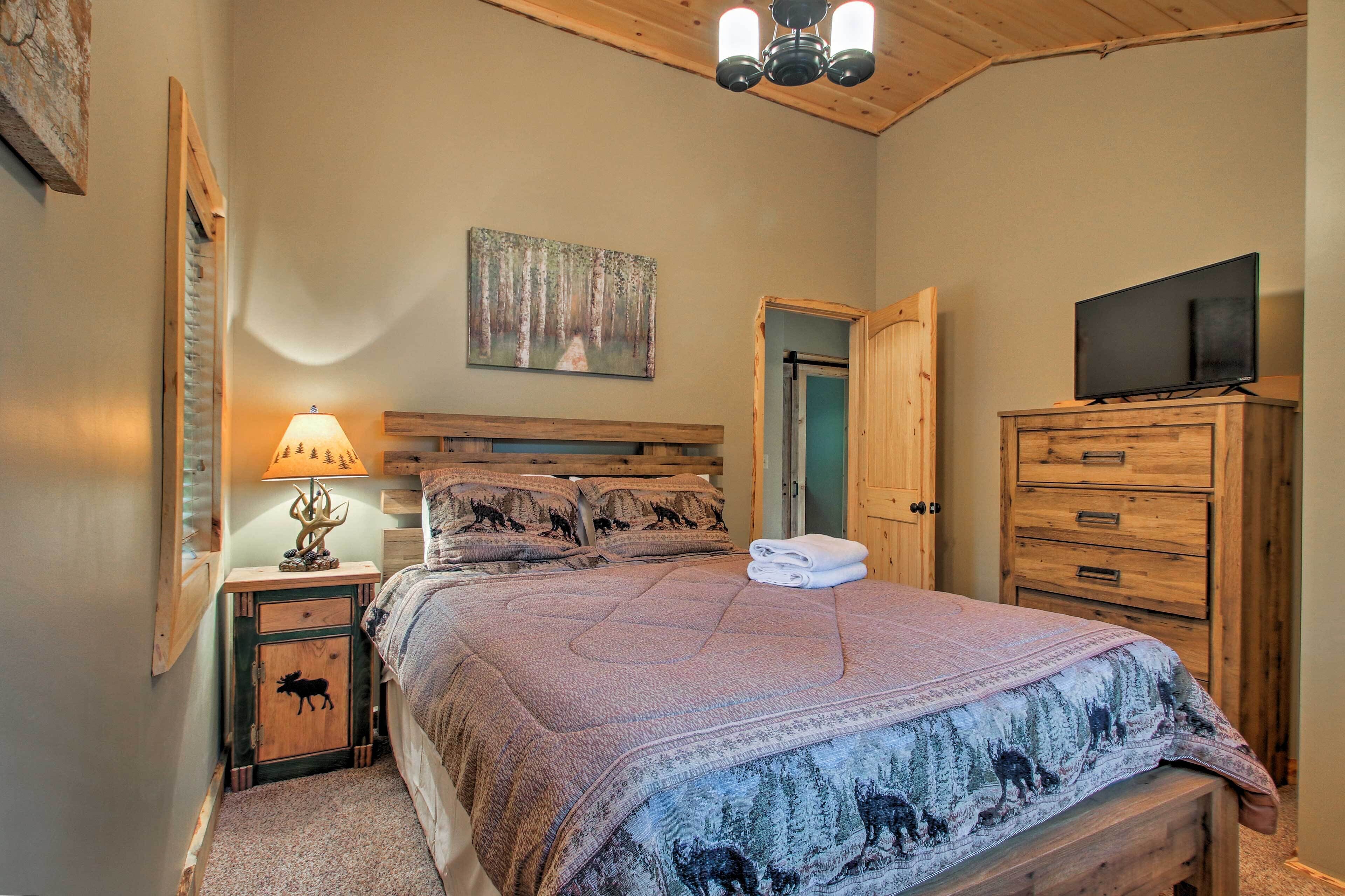 A bedroom with a bed, a nightstand with a lamp, a dresser, and a television on a dresser.