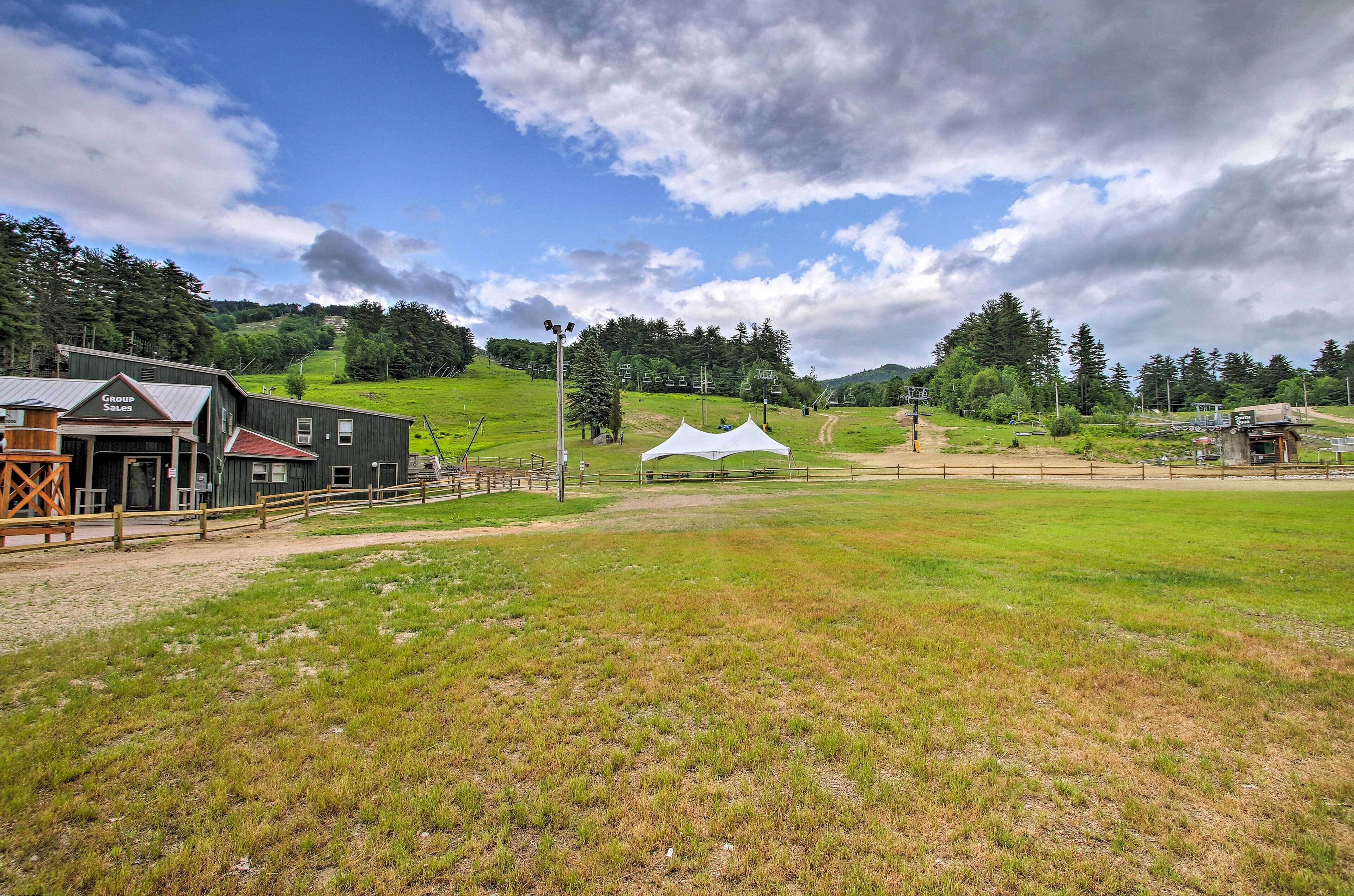 A rural setting with a barn, a white tent, and a fenced area.