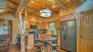 A rustic kitchen with wooden cabinets, a central island, and a stainless steel refrigerator. - Timber Home: Walk to Slopes & N Conway Shops! (North Conway)