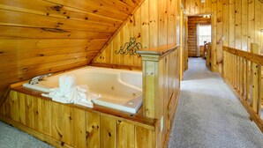 A wooden cabin interior with a wooden staircase, a wooden bathtub, and a carpeted floor. - Sevierville Cabin w/ Hot Tub, Views & Pool Access! (Sevierville)