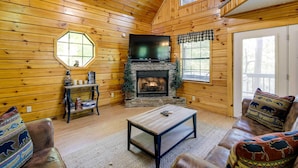 A cozy log cabin interior with a fireplace, wooden walls, a sofa, and a coffee table. - Sevierville Cabin w/ Hot Tub, Views & Pool Access! (Sevierville)