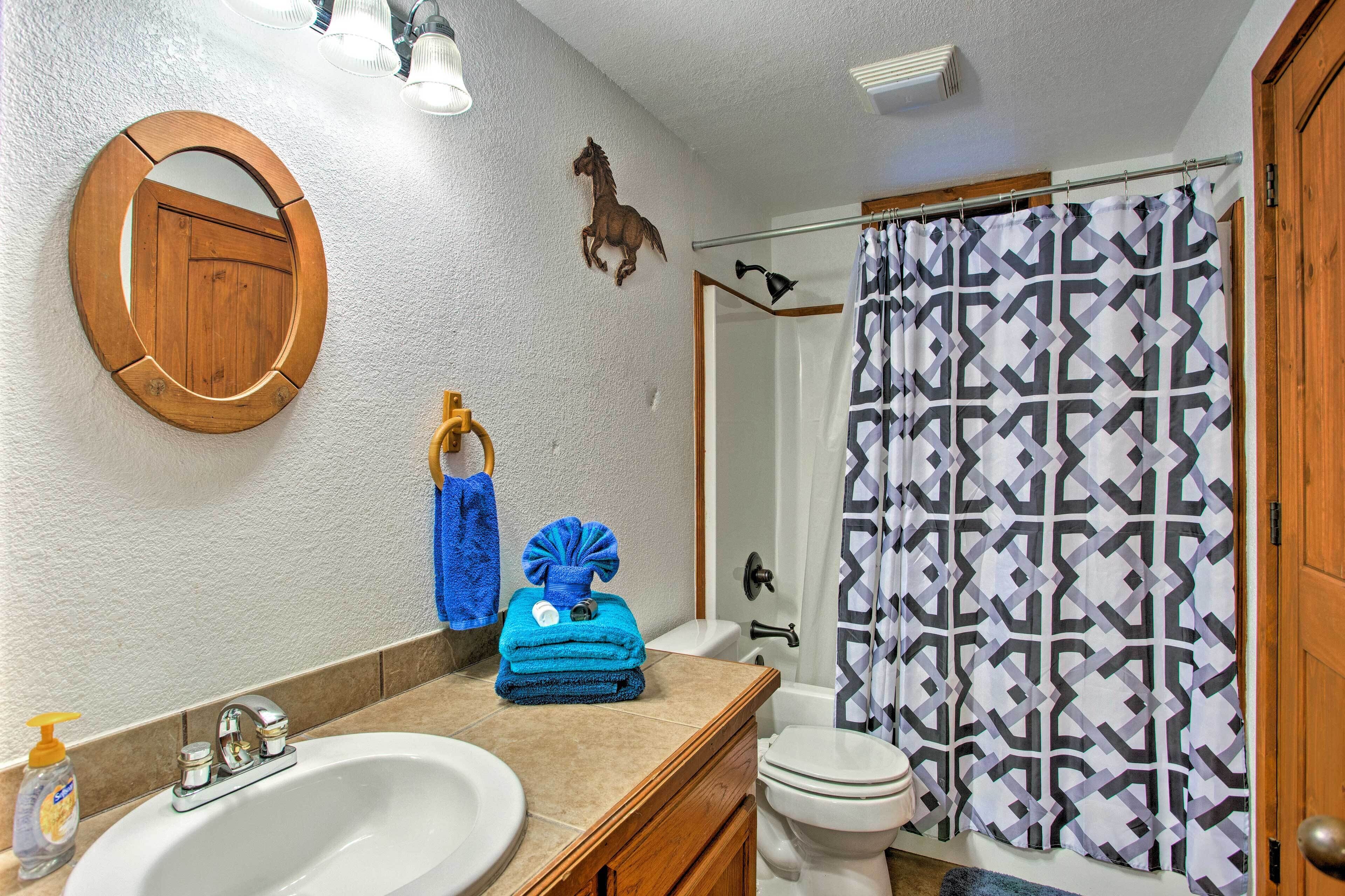 Une salle de bain avec un meuble-lavabo en bois, un évier, des toilettes et un rideau de douche à motifs géométriques.