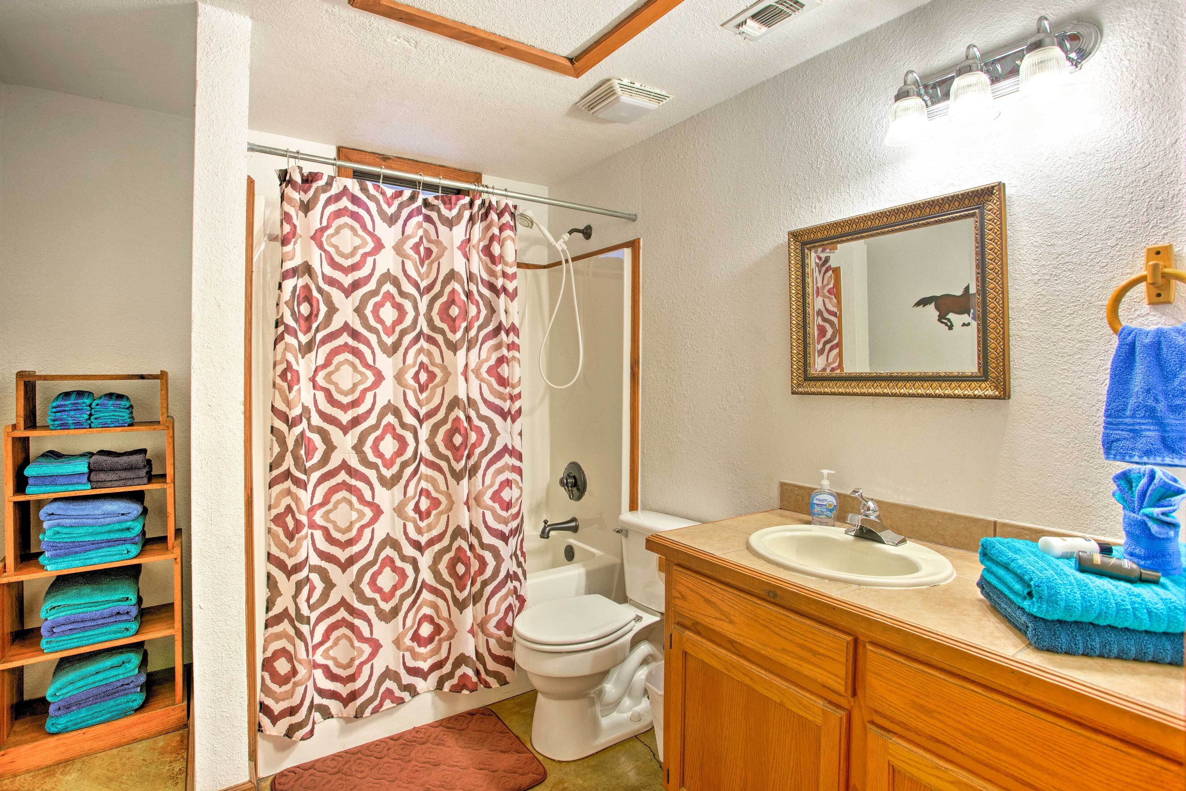 A bathroom with a shower curtain, toilet, sink, and a towel rack with towels.