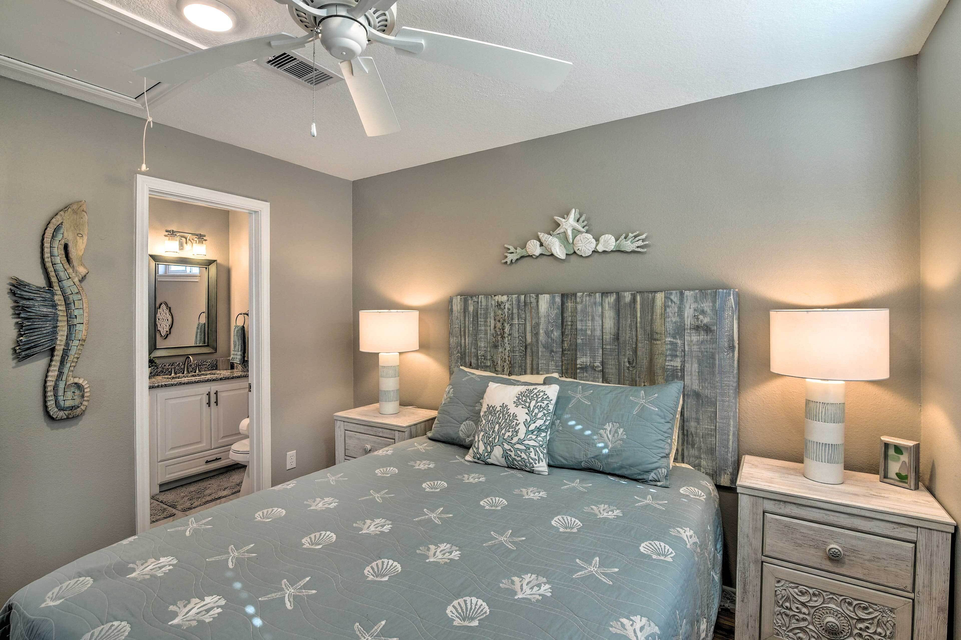 A bedroom with a bed, nightstands, a ceiling fan, a mirror, and a wall decoration.