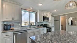 Una cocina moderna con armarios blancos, electrodomésticos de acero inoxidable y encimera de granito.