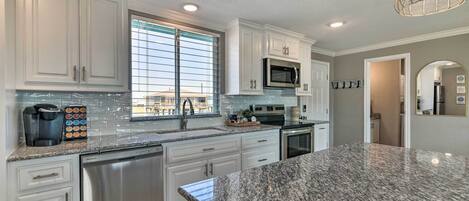 A modern kitchen with white cabinets, stainless steel appliances, and a granite countertop.