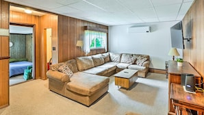 Een moderne woonkamer met een modulaire bank, een klein bijzettafeltje en een televisie op een houten standaard.