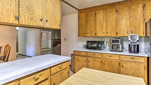 A kitchen with wooden cabinets, a microwave, a coffee maker, and a dishwasher. - Willow Creek Hideaway w/ Deck, 1 Mi to River! (Willow Creek)