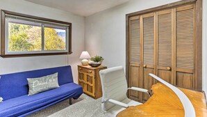 A room with a blue sofa, a white chair, a wooden cabinet, and a large wooden door. - Willow Creek Hideaway w/ Deck, 1 Mi to River! (Willow Creek)
