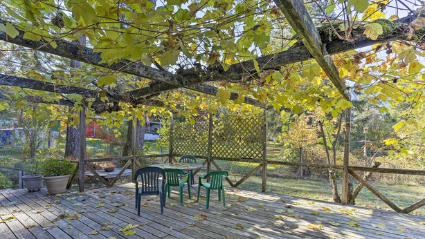 A wooden deck with a table and chairs, surrounded by a wooden pergola and foliage. - Willow Creek Hideaway w/ Deck, 1 Mi to River! (Willow Creek)