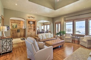 A spacious living room with a large sofa, armchairs, and a coffee table. There are wooden cabinets and a dining area visible in the background. - Bozeman Getaway on the Prairie w/ Patio & Grill (Bozeman)