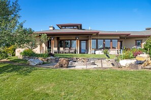 A two-story house with a large patio area, stone walls, and a well-maintained lawn. - Bozeman Getaway on the Prairie w/ Patio & Grill (Bozeman)