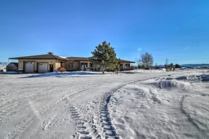 Een huis met een garage, oprit en een besneeerd landschap.