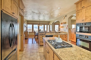 A spacious kitchen with wooden cabinets, a granite countertop, a stainless steel refrigerator, a gas stove, and a built-in oven. - Bozeman Getaway on the Prairie w/ Patio & Grill (Bozeman)