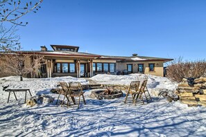 A house with a stone fire pit and two wooden chairs in the snow. - Bozeman Getaway on the Prairie w/ Patio & Grill (Bozeman)