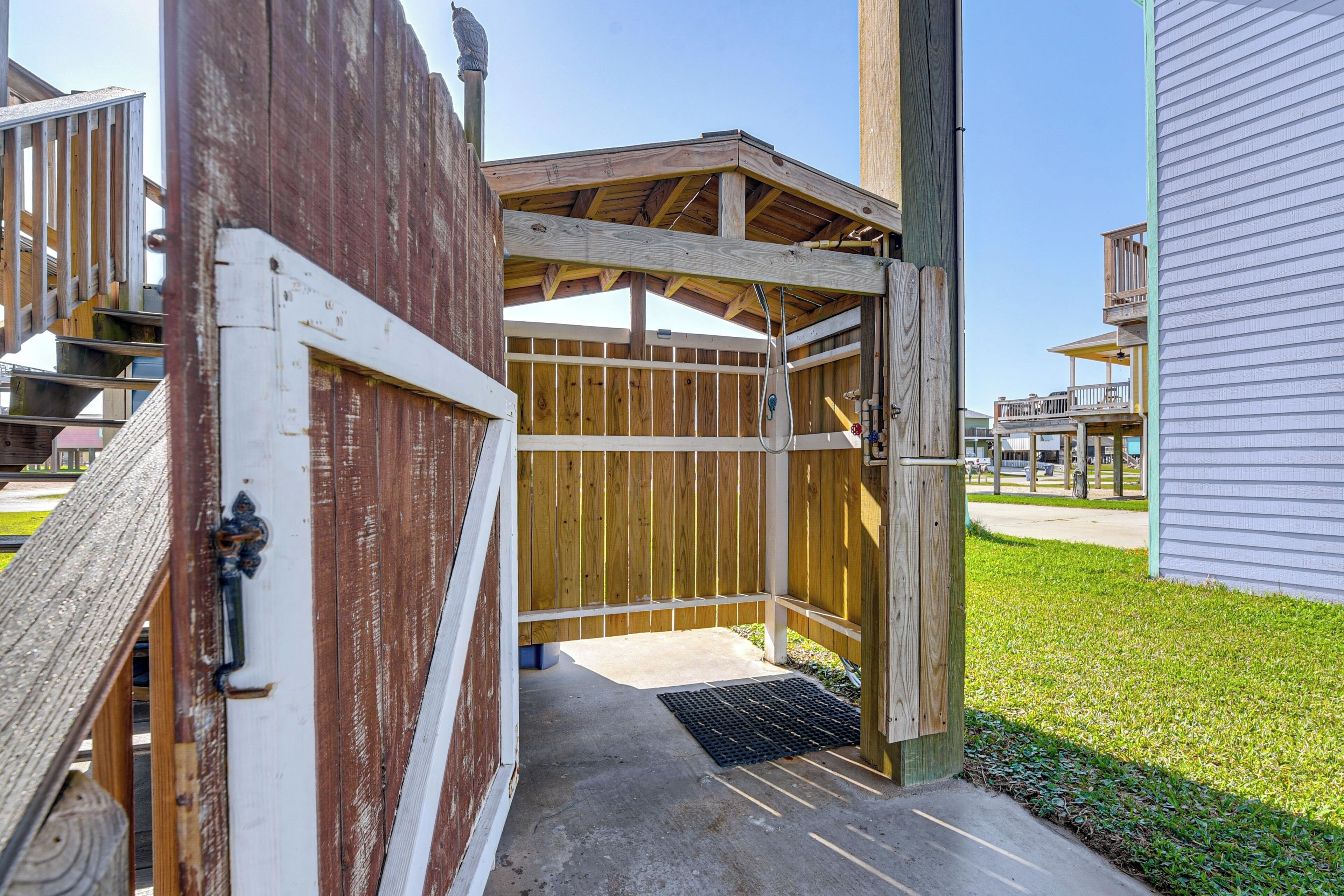A wooden structure with a metal door, a concrete floor, and a grassy area in the background.
