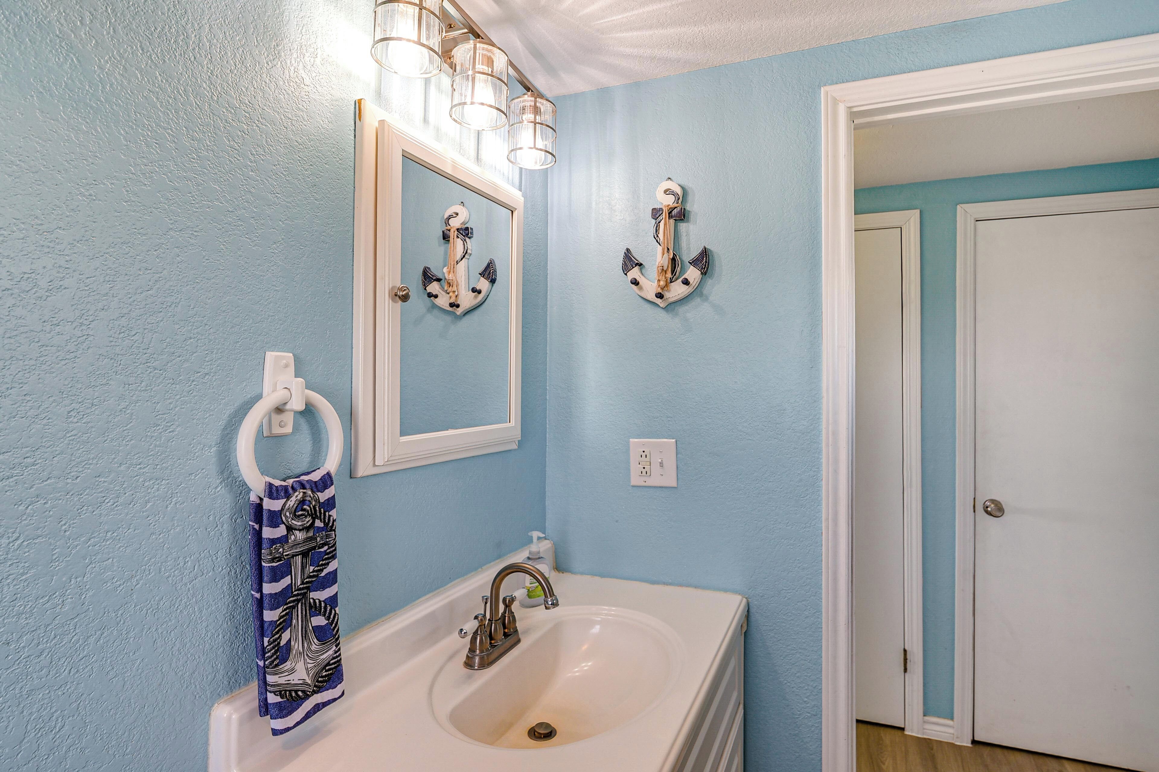 A bathroom with a sink, mirror, and two wall-mounted light fixtures.