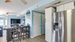 A kitchen with a stainless steel refrigerator, a dining table with chairs, and a ceiling fan. - 1 Block to Surfside Beach: Home w/ Deck! (Freeport)