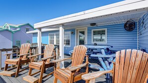 A covered deck with wooden chairs, a table, and a blue house in the background. - 1 Block to Surfside Beach: Home w/ Deck! (Freeport)