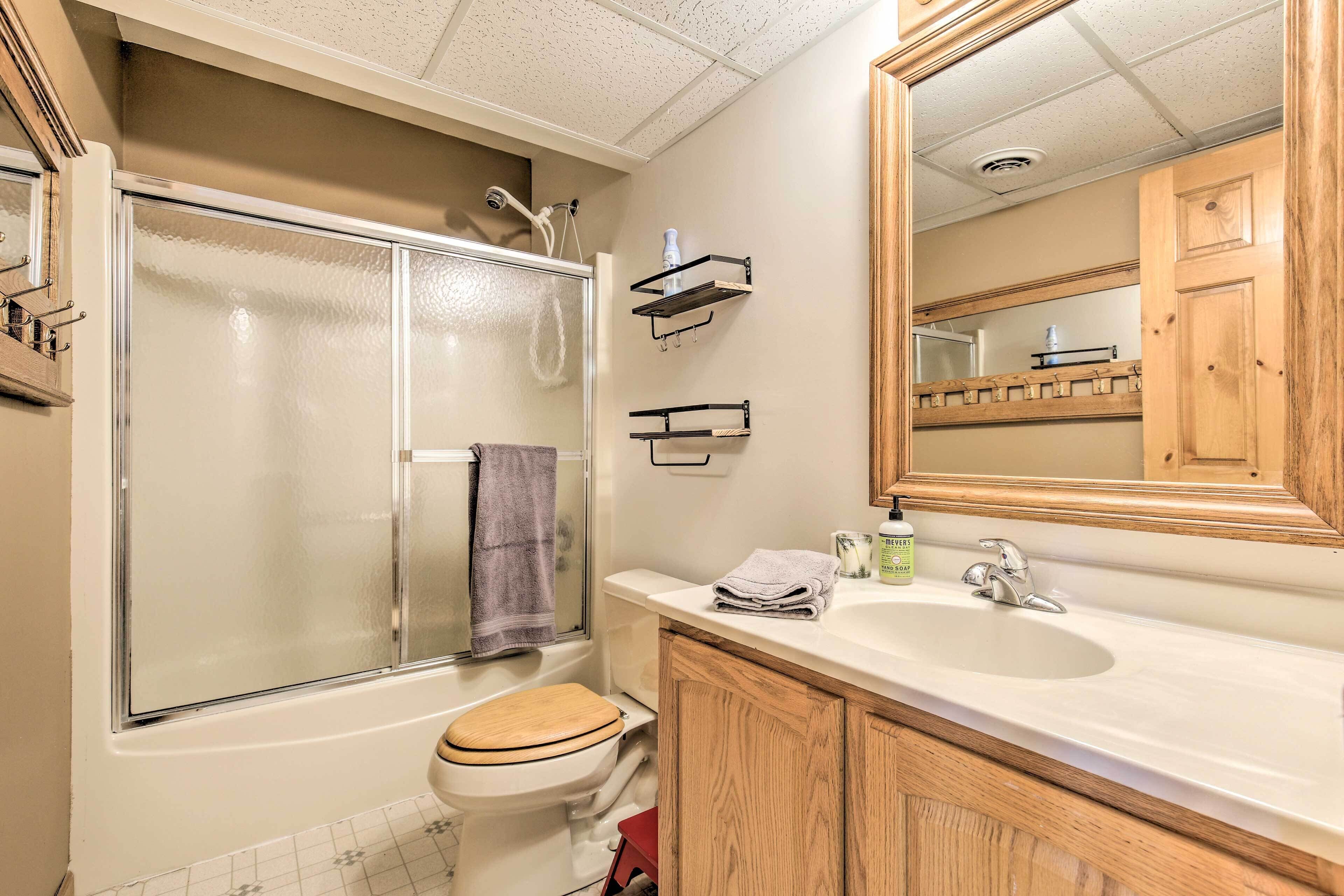 A bathroom with a bathtub, toilet, and sink. There are wooden cabinets, a mirror, and a towel rack.