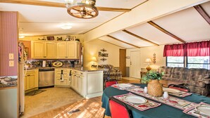 A spacious kitchen with wooden cabinets, a dining area with a table set for four, and a cozy living room with a couch. - Waterfront House w/ Boat Slip on Lake Eufaula! (Canadian)